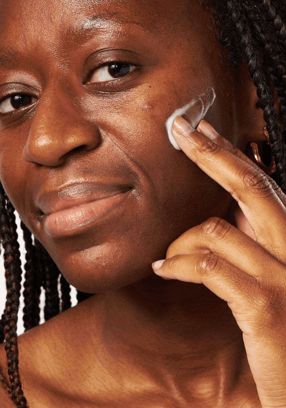 Woman applying facial acne treatment to her cheek.