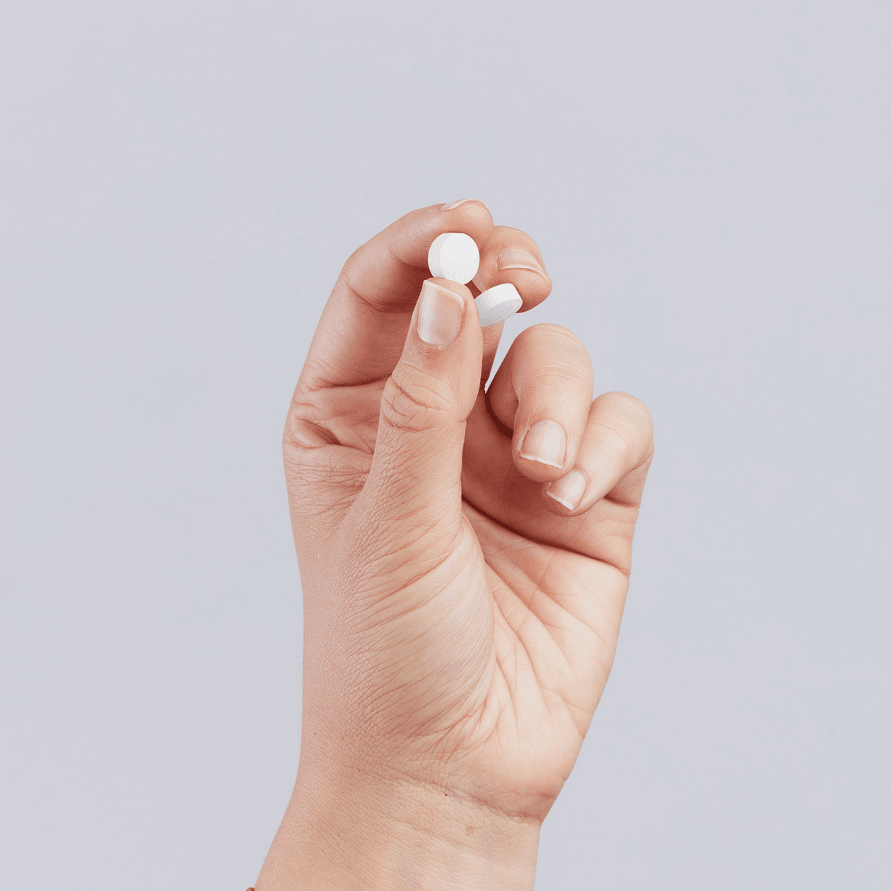 Hand holding two pills of Sulfamethoxazole-Trimethoprim.